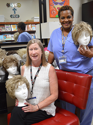Ruth Cummins, UMMC assistant director for media relations, seated, and her siblings donated their mother's wigs and many stands to the Patient Resource Center. Resource Center manager Janice Johnson helped set them up.
